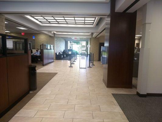 entry area, with line for tellers on he right.   note bank officer on left wearing mask