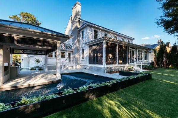 Backyard landscaped with an outdoor kitchen, paver and planters around the pool