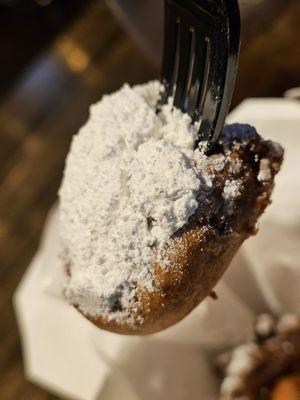 Close-up of a black plastic fork holding a fried Oreo.