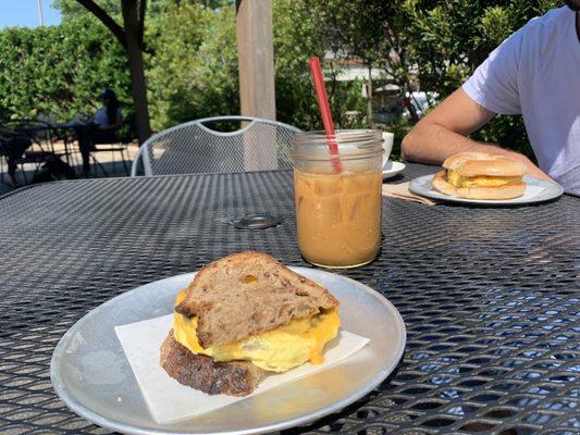 Egg sandwich with sausage on multigrain bread and an iced coffee