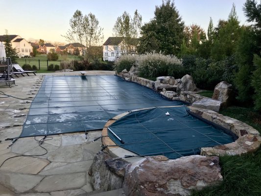 A beautiful pool with an attached spa. This pool has a double cable system holding the cover to the raised wall.