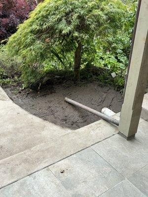 Hole neatly cut ,  dug under small patio, refilled hole, neatly sculpted remaining soil under nearby tree, hosed patio