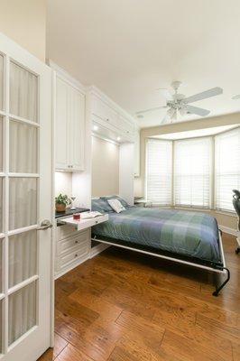 Open wall bed unit with pull-out shelves for temporary counter space.