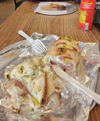 A slice of Margherita and a cheese roll with mortadella and pistachio.  With a blood orange soda too