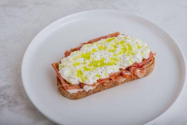 Prosciutto Crostini. Prosciutto Di Parma, Stracciatella Cheese, Basil Oil, Cracked Black Pepper on Sourdough Toast