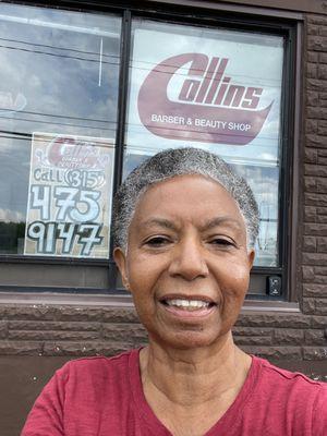 Jill with a fresh haircut standing in front of Collins Barber Shop