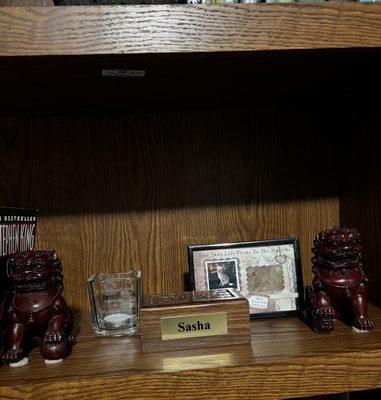 Votive with engraving, wood box with ashes inside, and a picture frame with a photo, fur, and her birthday.