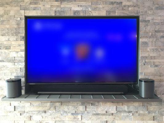 TV mounted in an inset cubby above a fireplace, with Sonos Playbar.