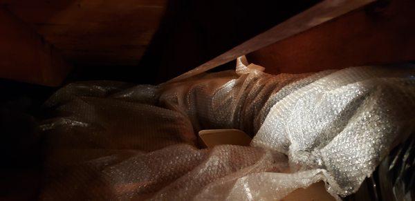 Plastic bubble wrap on deck of attic with small bucket collecting water