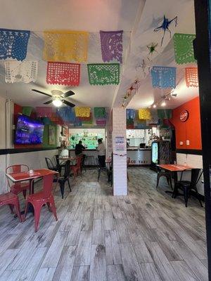 Inside of the restaurant with a mini bar on the left side and the food on the right side and kitchen behind it.