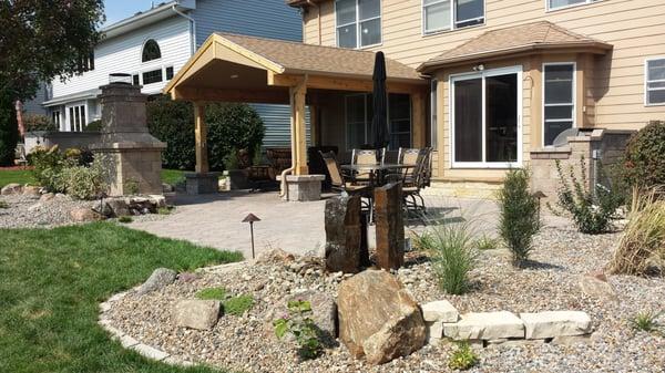 Covered patio with fireplace, grill Island, water feature and landscaping.