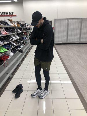 A man trying on Fila shoes in the men's footwear section.