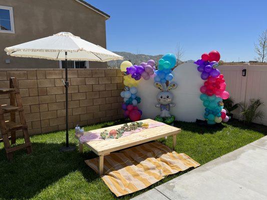 Balloon decorations with backdrops, picnic table, umbrella and stand that could be used in various ways.