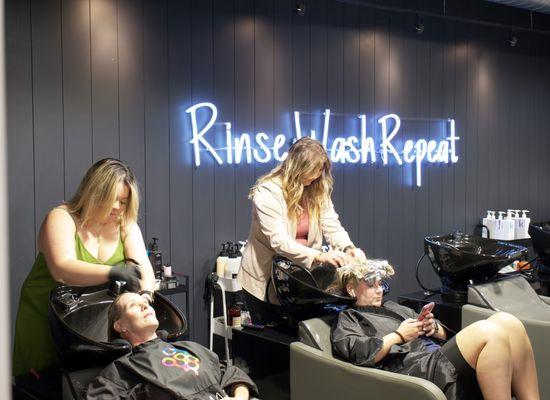 Jess and Logan in the shampoo area with their clients