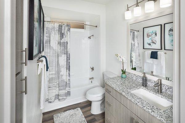 Upgraded bathrooms feature wood grain cabinets and framed mirrors