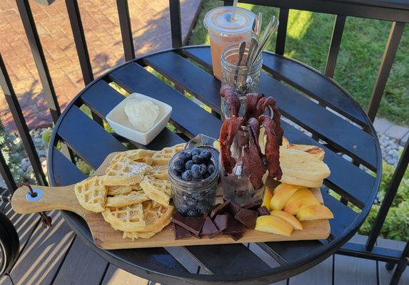 Saturday Brunch Charcuterie - Waffles, bagels, bacon, boiled eggs, apples, blueberries, chocolate, butter, and syrup.