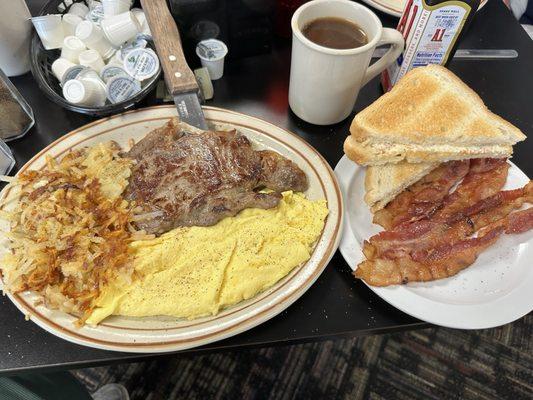 Ribeye steak, scrambled eggs, hash browns, white toast and bacon.