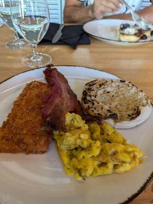 Old and cold Scrambled Eggs and Bacon with a brick of greasy cold Hash Browns and a half a piece of English Muffin.