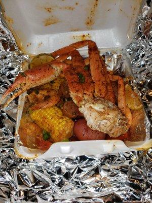 Seafood box consisting of shrimp, sausage, potatoes, corn and crab legs.