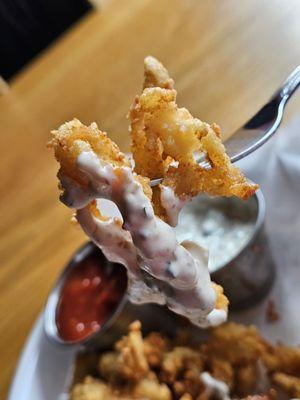 A fork holding the clam strips with the tartar sauce.