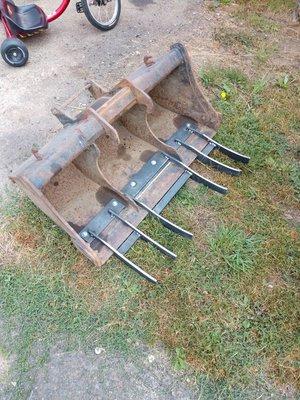 Overburden rake attachment for a backhoe