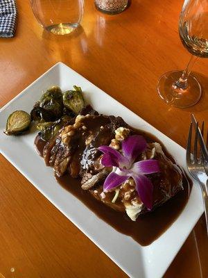 Beef brisket with mashed potatoes and roasted Brussel sprouts, garnished with an orchid blossom.