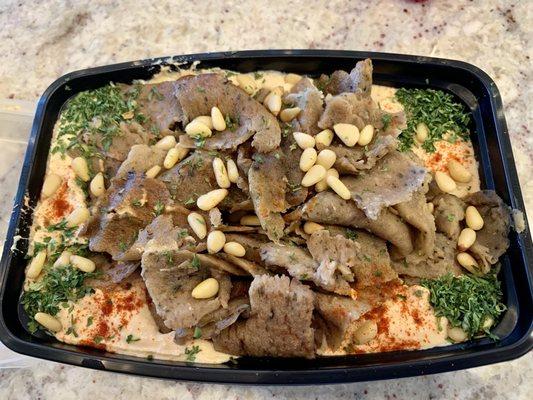 Spicy hummus and lamb gyro appetizer, in a to go container.