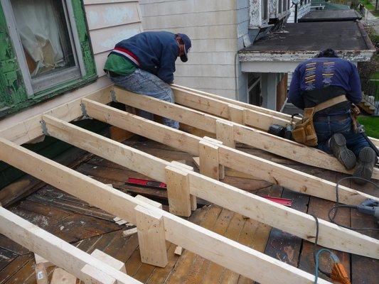 Flat roof transition into a sloped shingle roof.