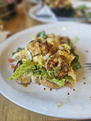 Avocado toast with light avocado, scrambled eggs, shrimp and spicy sauce drizzled on top.