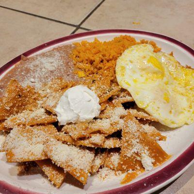 Chilaquiles con huevo served with rice and beans topped with Cotija cheese and Sour Cream