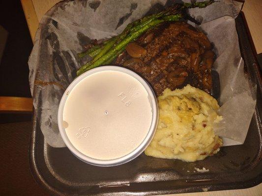 Chopped steak with asparagus and mashed potatoes. Gravy on the side.