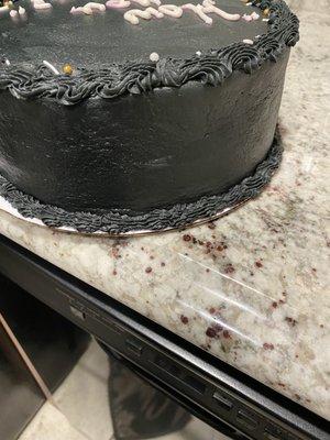 Back of the cake was pushed all the way to the end against cardboard box Black icing.