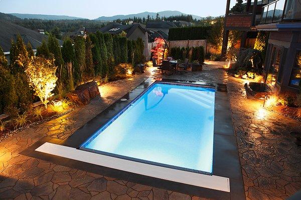 Pavers, colorful night lighting, and plantings around a pool can enhance any backyard resort.