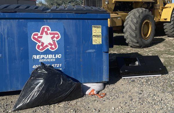 Closer picture of dumpster dropped on bags of garbage after pickup