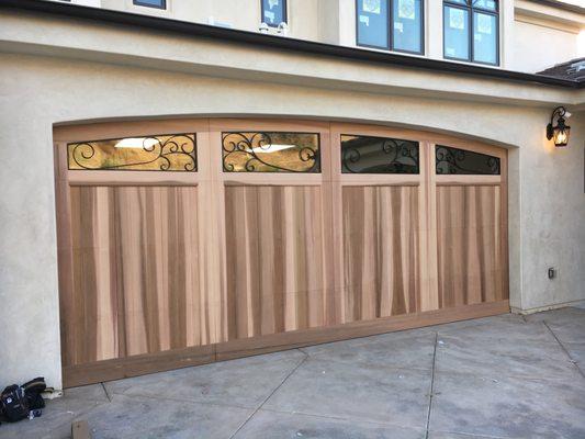 Stained grade wood door with custom wrought Iron windows.