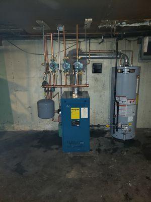 Another mechanical room by ZSL . Pictured here is 
a Burnham X2 gas fired boiler in combination with an A.O Smith gas fired water heater .