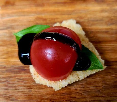 Cute Ladybug  made from cherry tomato, basil  balsamic vinegar on a cracker.