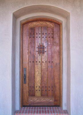 Arched rustic fir entry door with speakeasy and wrought iron grill