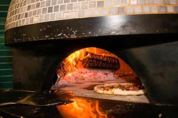 Wood-fired pizza being cooked.