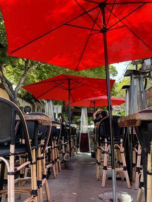 Relax beneath vibrant red umbrellas on our charming outdoor patio, where every moment is bathed in warm ambiance.