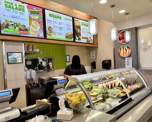 Menu of salads, wraps, and paninis; employee with ingredients