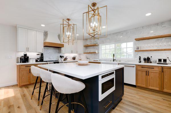 Kitchen with warm wood cabinetry, navy island, marble countertops, brass fixtures, and high-end appliances for timeless sophistication.