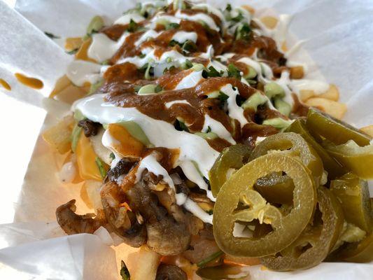 Mushroom (Fries) Papas Fritas with nacho cheese, beans, onion, cilantro, guacamole, crema and jalapeños.