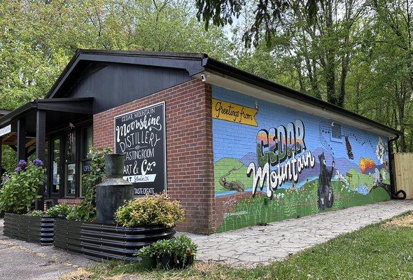 Our Cedar Mountain Moonshine Distillery showing our Postcard Mural designed and painted by our family artist "Dear Sarah".