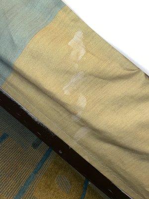 A white stain on the bed skirt of one of the beds.