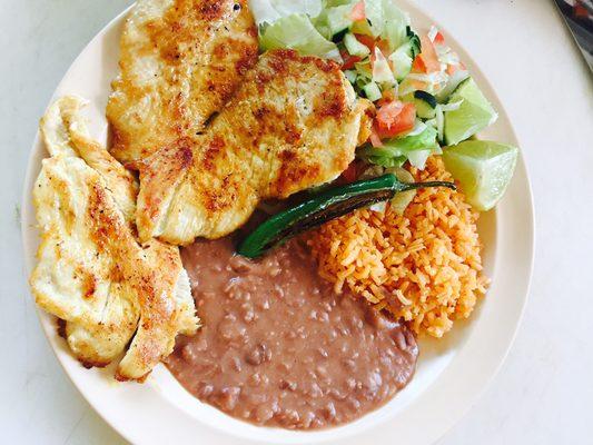 Grilled chicken breast refried beans, rice and salad on side