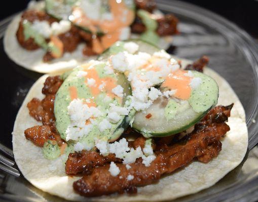 Spicy pork tacos with pickled cucumbers, creamy sriracha sauce & queso fresco.