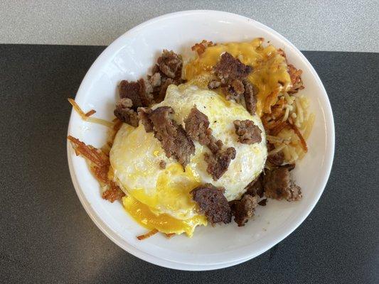 Hash brown bowl with over easy eggs, hash browns, sausage and jalapeños.