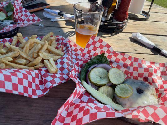 Two cheeseburgers and a basket of fries with a draft Bluemoon