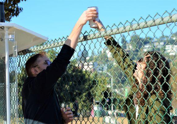 Austin handing a beverage to a customer in the dog park